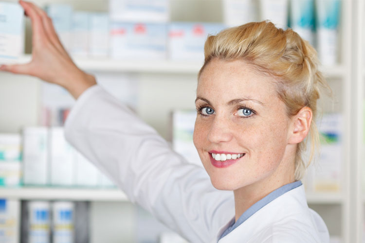 Apothekerin, die Produkte aus dem Regal holt
