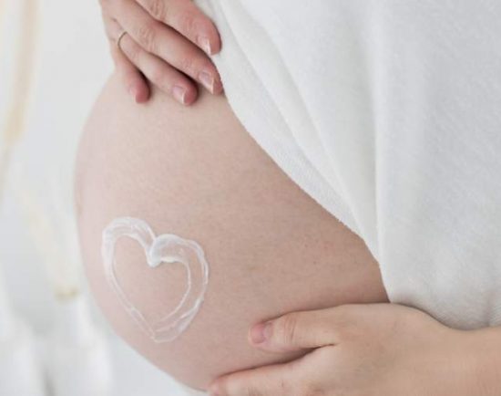 Frau mit Herz aus Pflege auf dem Bauch