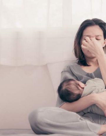 Traurige Frau mit ihrem Baby auf dem Arm