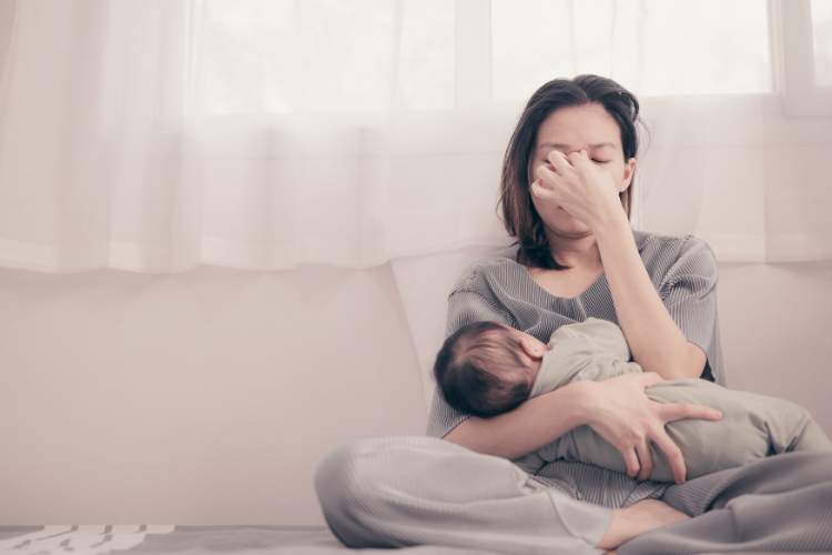 Traurige Frau mit ihrem Baby auf dem Arm